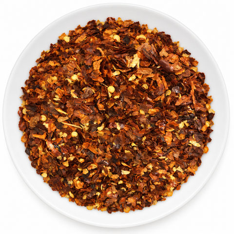 Chili Pepper Crushed dry product on a plain white plate against a white background