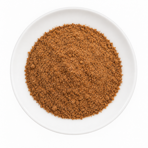 Nutmeg, ground dry product on a plain white plate against a white background