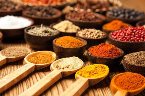 Colorful spices arranged in wooden bowls and spoons.